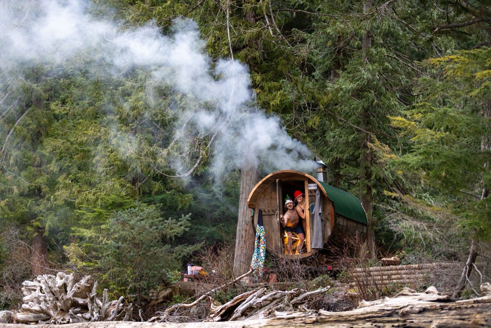 Steam pouring out of the restored barrel sauna with two guests in the doorway